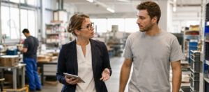 Werkgever en medewerker bespreken arbeidsomstandigheden en risico’s tijdens een rondgang op de werkvloer.